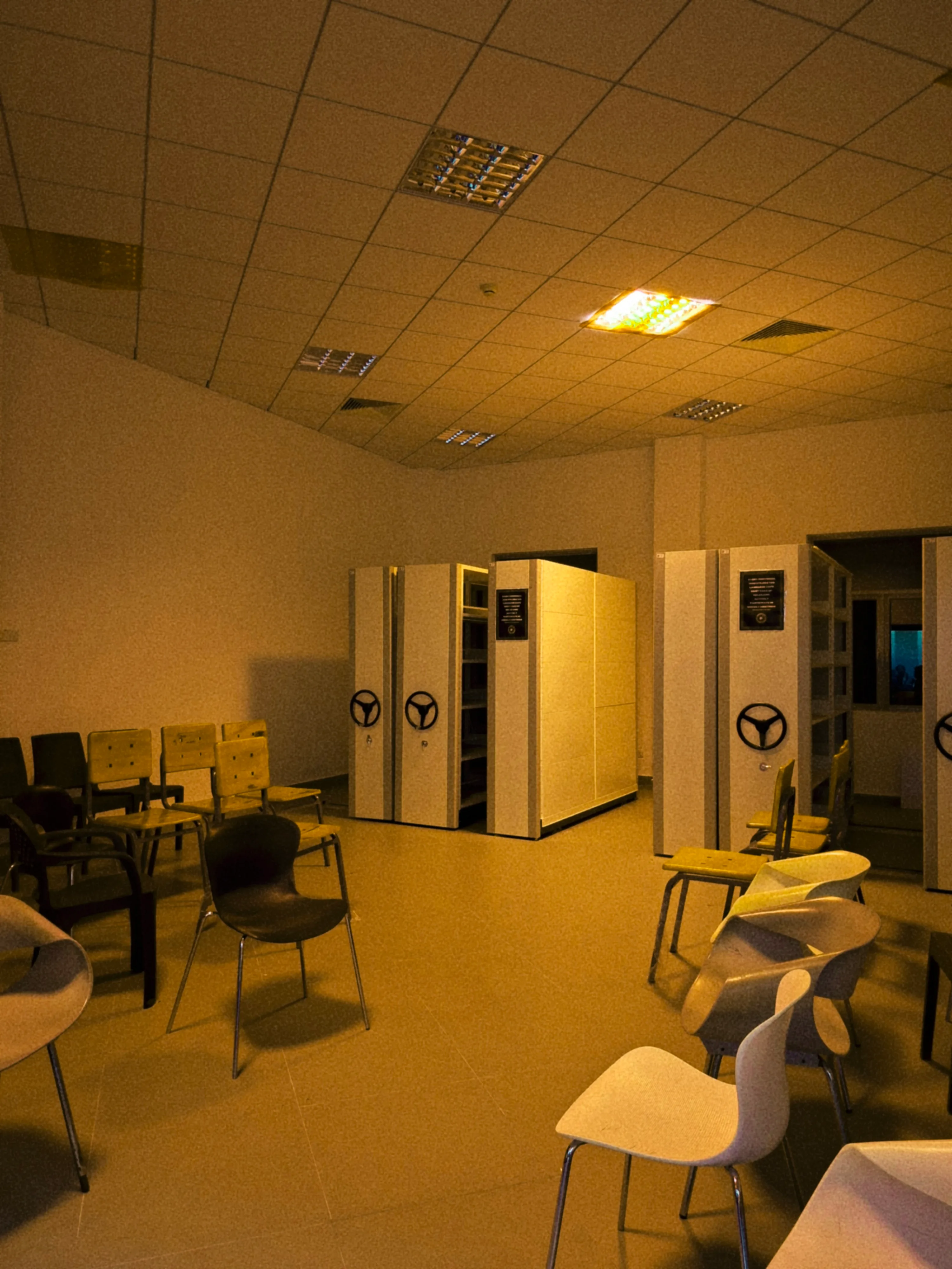 A dim room of compact shelving and clustered chairs
