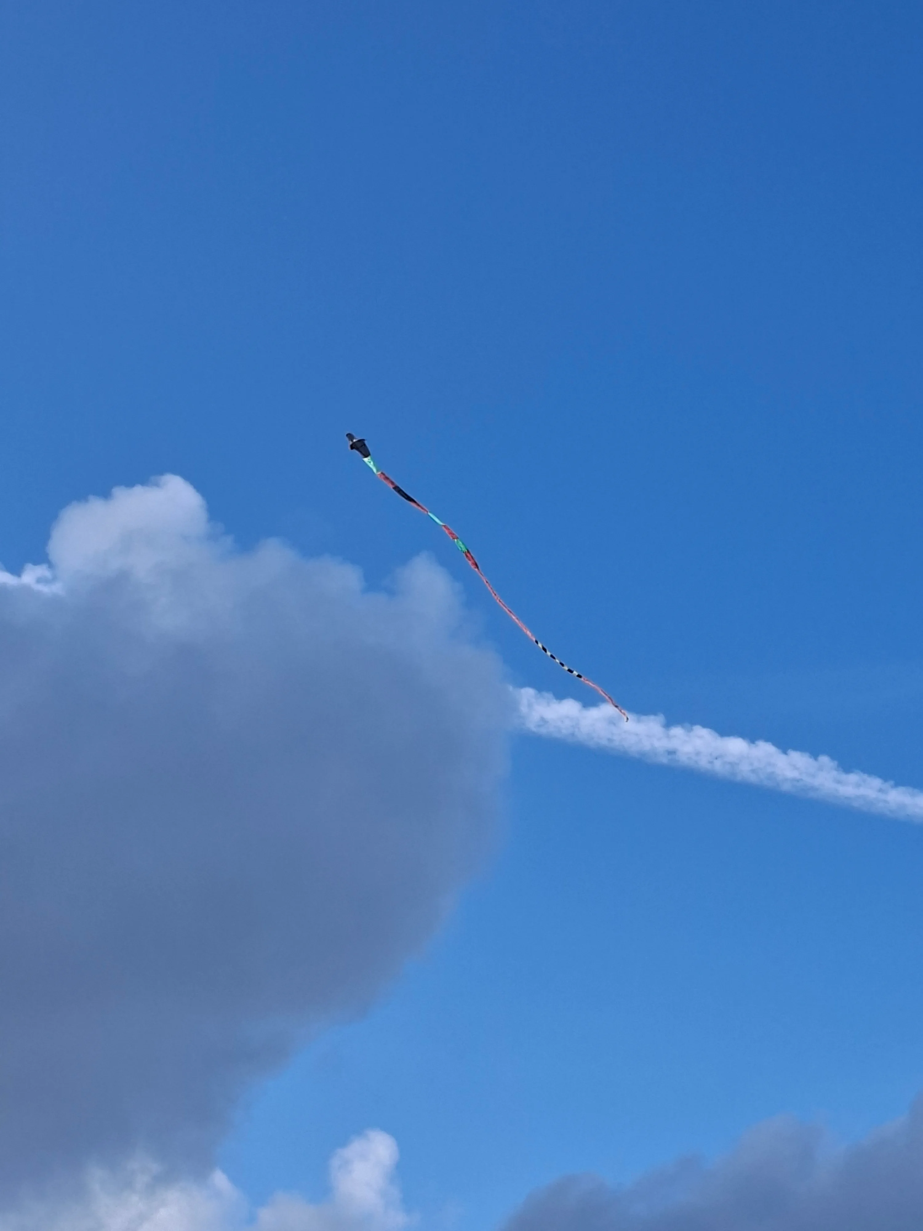 A colorful kite tail crossing a blue sky
